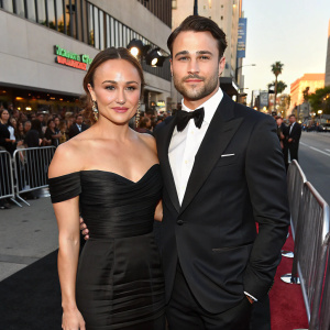 Briana Evigan and Ryan Guzman at an exclusive premiere event. She is in a chic black off-shoulder gown. He wears a classic tuxedo. Crowded street background