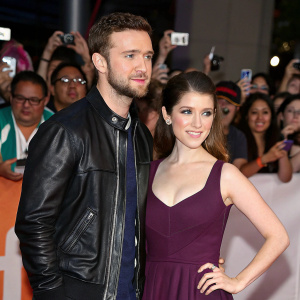 Justin Timberlake and Anna Kendrick at a high-profile premiere event. Justin in a black leather jacket, Anna in a deep purple sleeveless dress. Crowd of diverse fans using smartphones to capture the moment.