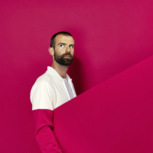 Steven Defour, Belgian footballer, intense gaze. Press conference at UEFA Champions League. Solid black backdrop.