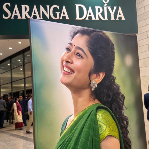 Sai Pallavi, in a vibrant green saree, posing for 'Saranga Dariya' movie poster. Large format advertisement featuring her smiling face prominently