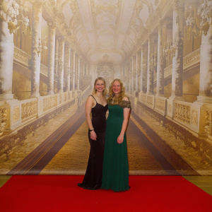 Imogen Poots and Toni Collette at the annual film gala, posing in front of a grand backdrop adorned with various sponsor logos.