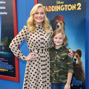 Elisabeth Rohm and her daughter Easton August Anthony Wooster at the Paddington 2 premiere. Elisabeth in a polka-dotted dress, clutch in hand, stands alongside Easton in a camouflage shirt, both in front of the movie poster.