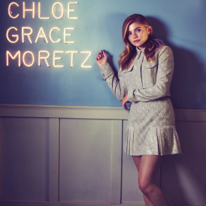 Chloë Grace Moretz, young actress, standing against a gradient blue backdrop with white text quote from a famous novel.