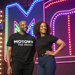 Brandon Victor Dixon and Vallisia LeKae, dressed in black t-shirts with 'Motown The Musical' logo, standing in front of a vibrant neon backdrop at a theater event.