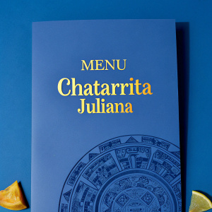 Vibrant menu for Chatarrita Juliana. Rich orange background adorned with intricate Aztec motifs. 'Menu' and 'Chatarrita Juliana' elegantly centered in bold, cursive script.