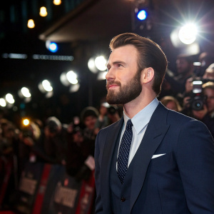 Chris Evans at a movie premiere, wearing a navy suit and tie. Bright lights and paparazzi surrounding him.