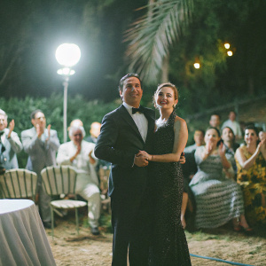 Andy Garcia and Daniella Garcia-Lorido at a glitzy Hollywood gala. Both in formal wear, posing together in a spotlight. Audience clapping in the background