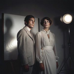 Gian Maria Volonté and Carla Gravina in a dimly lit, vintage photograph. They stand in a minimalist studio setting.