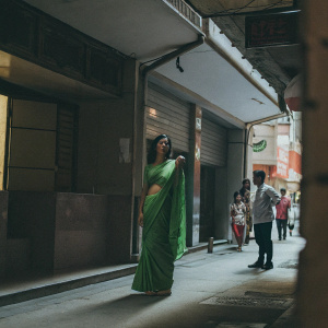 Radhika Pandit, Indian actress, graces the cover of a fashion magazine. Dressed in a vibrant green saree, posing confidently on a bustling city street.
