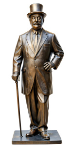 A bronze statue of Hercule Poirot as played by David Suchet, a bowler hat on his head, fine mustache, hands in gloves, with a walking cane