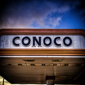 Conoco's logo, featuring bold black sans-serif letters against a bright blue backdrop, showcasing the brand name and location in an elegant, modern style.