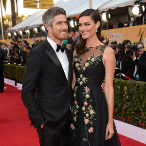 Dave Annable and Odette Annable attend a glamorous awards show. Dave in sleek tuxedo, Odette in chic, black gown with floral embroidery. Crowded red carpet, flashing cameras