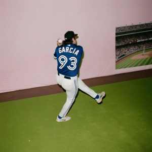 Yimi García in a striking action shot, mid-pitch with intense focus. Wearing a blue jersey with his name 'Garcia' and number '93'. The stadium backdrop is bustling with a cheering crowd.