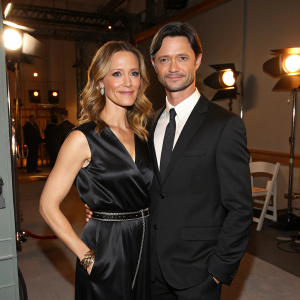 KaDee Strickland and Jason Behr at the CNN studios. Strickland in a black satin dress with a belt-like accent. Behr in a black suit and tie.