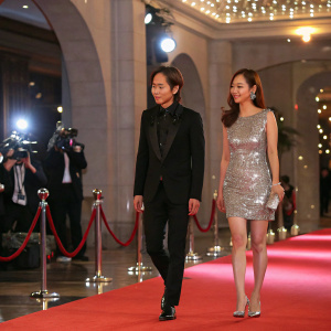 Jang Keun-Suk and Kim Jeong-Ju at a glamorous awards show. Jang in a black suit, Kim in a silver sequined dress. Red carpet with flashing lights and photographers.