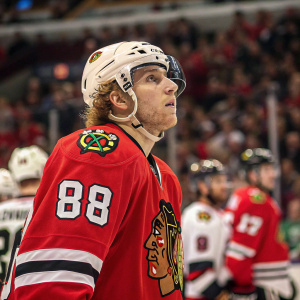 Photograph of Patrick Kane, Chicago Blackhawks player. Wearing number 88 jersey. Intense look on face, amidst bustling crowd at hockey game.