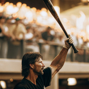 Randy Johnson, the baseball legend, captured in an intense pose. Dark jersey, bat raised. Crowd blurred in the background.