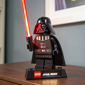Darth Vader LEGO figure lamp. Detailed, black and red design. Standing confidently with a red lightsaber. Close-up shot. LEGO Star Wars logo at the base.