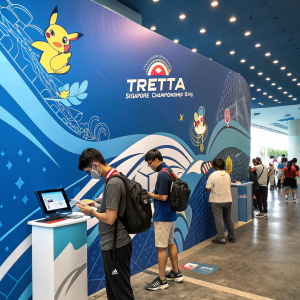Welcome to the Pokemon TRETTA Singapore Championship 2019, where strategy meets skill. This tournament invites Pokemon trainers to compete and showcase their talent. To participate, follow these steps:

1. Ensure you have a current Pokemon game version that supports the TRETTA system.
2. Register online at the official TRETTA website. A valid ID and game version verification are required.
3. Choose your preferred battle category during registration: Singles, Doubles, or Mixed Teams.
4. Confirm your participation before the deadline. Late entries may incur a fee.
5. On the day of the championship, arrive at the Singapore Expo Hall by 9 AM for check-in.

The event features a vibrant backdrop of blue hues and creative design elements. It’s a mix of dynamic graphics and soothing tones, creating an engaging atmosphere for all participants and spectators.