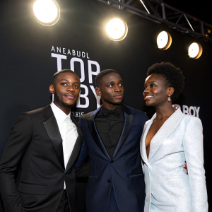 Hope Ikpoku Jnr, Michael Ward, and Araloyin Oshunremi at the Top Boy 2 premiere. Stark contrast against a black backdrop with bright stage lights.