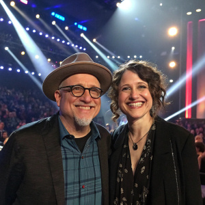 Bobcat Goldthwait and Nora Muhlenfeld, smiling, at a TruTV awards ceremony. Bright stage lights and audience visible