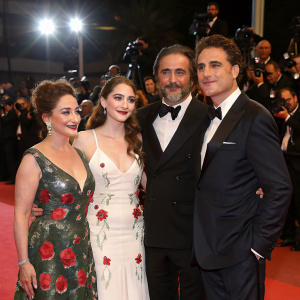Gloria Estefan, Chloe Fineman, Andy Garcia, and Casey Thomas Brown posing at the premiere night of a major film festival. Lavish red carpet, flashing cameras, excited crowd.