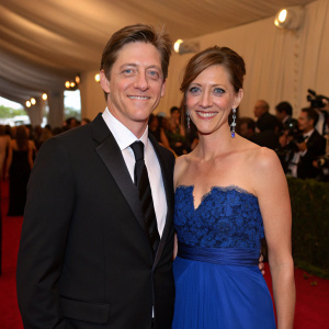 Kevin Rahm and Amy Lonkar Rahm at gala event. Kevin in black suit, Amy in blue gown. They pose together, smiling, with crowd in background.