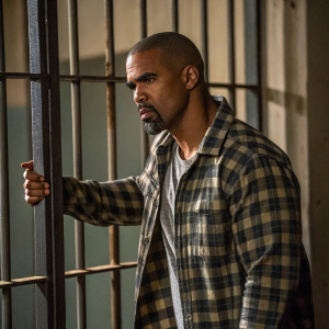 Shemar Moore, starring in gritty prison drama. Dressed in plaid shirt, standing before metal bars. Dimly lit, camera focused on his determined face.