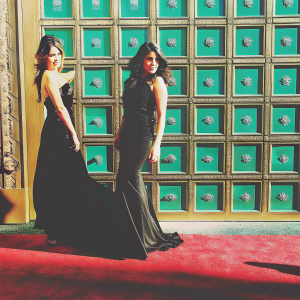 Camila Cabello and Lauren Jauregui from Fifth Harmony at the iHeartRadio Music Awards. Red carpet event, black dresses, standing against a backdrop filled with NBC logos.