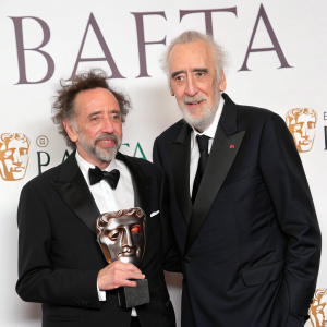 Tim Burton and Sir Christopher Lee at BAFTA Awards. Both in formal attire, white background with BAFTA logo