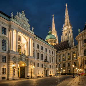 The Hofburg Imperial Palace in Vienna, Austria at night. Lit up, ornate architecture visible.