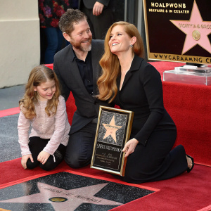 Amy Adams, Darren Le Gallo, and Aviana Olea Le Gallo celebrating at the Hollywood Walk of Fame. Star ceremony, Amy kneeling with framed award, Aviana seated beside her, against the backdrop of the Walk of Fame.