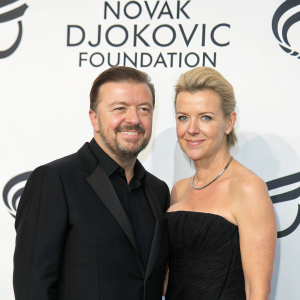Ricky Gervais and Jane Fallon attending the charity gala for Novak Djokovic Foundation. Ricky in black suit, Jane in black gown. White background with foundation logo