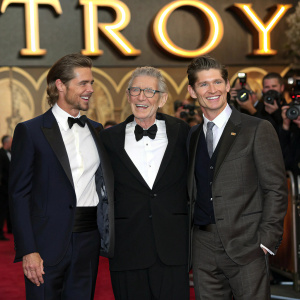 Brad Pitt, Peter O'Toole, and Eric Bana at the premiere of 'Troy'. Formal attire. Smiling. Red carpet event. Large, ornate golden backdrop.
