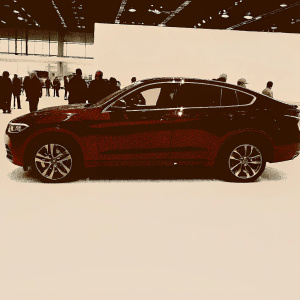 Red BMW X4 M40i showcased at a bustling auto expo. Shiny exterior, sleek design, people admiring in background