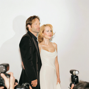 Gillian Anderson and David Duchovny attending a Hollywood premiere. Crowds of fans and paparazzi in the background.