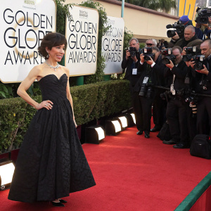 Sally Hawkins, in a black cocktail dress, at the Golden Globe Awards. She stands confidently on the red carpet amidst flashing cameras.