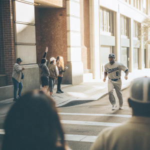 Kole Calhoun, wearing LA Angels jersey and uniform, running on a bustling city street, surrounded by fans and passersby.