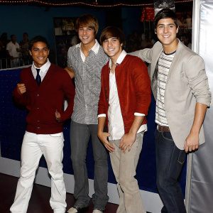 Carlos Pena Jr., James Maslow, Kendall Schmidt, and Logan Henderson of Big Time Rush. Promotional photo shoot. Neon lights and blurred crowd in background