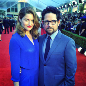 Katie McGrath, with wavy hair and a warm smile, and J.J. Abrams, sporting a beard and serious expression, attending the Screen Actors Guild Awards. Crowded red carpet.