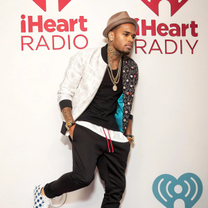Chris Brown in stylish outfit. White backdrop with iHeart Radio and Pool Party logos.