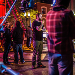 Alex Pettyfer, featuring detailed tattoos. A candid shot on set of Beastly, casual attire, surrounded by film crew.
