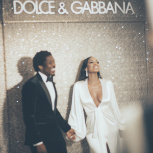Nick Cannon and Selita Ebanks at the Dolce & Gabbana gala. Cannon in a classic black tuxedo, Ebanks in a stunning white gown with a plunging neckline. Glittering silver backdrop with Dolce & Gabbana logo