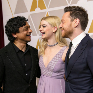 M Night Shyamalan, Anya Taylor Joy, and James McAvoy at an awards ceremony. Caucasian James McAvoy with short hair and neatly trimmed beard, South Asian M Night Shyamalan with curly dark hair, and Caucasian Anya Taylor Joy with casual blonde hair, posing candidly on a black carpet.