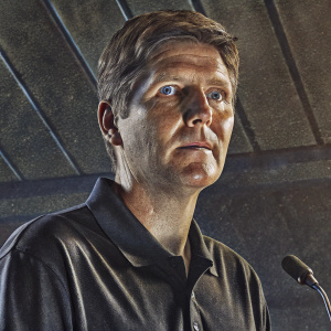 Oliver Glasner, head coach of Eintracht Frankfurt, at a press conference. Wearing a black polo shirt. Staring intensely at the camera.