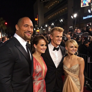 Dwayne Johnson, Carla Gugino, Alexander Ludwig, and AnnaSophia Robb attend a Hollywood movie gala. Crowded red carpet with flashing cameras.