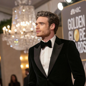 Richard Madden at the Golden Globe Awards. Black tuxedo. Shimmering chandelier in the background.