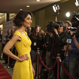 Necar Zadegan at a press conference. Dressed in a vibrant yellow dress. Behind her, a crowd of journalists and cameras.