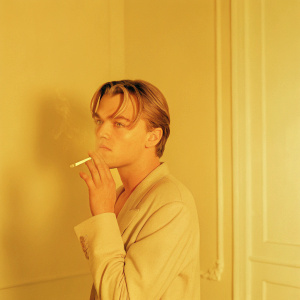 Leonardo DiCaprio, in a vintage black and white photo, smoking a cigarette. Dimly lit room, blurred background.