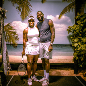 Serena Williams and LeBron James posing by the beach. Behind them, a backdrop with corporate logos.